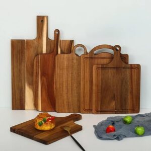 Set of wooden cutting boards in different sizes arranged against a light background; a small pastry rests on one board with a fork nearby.