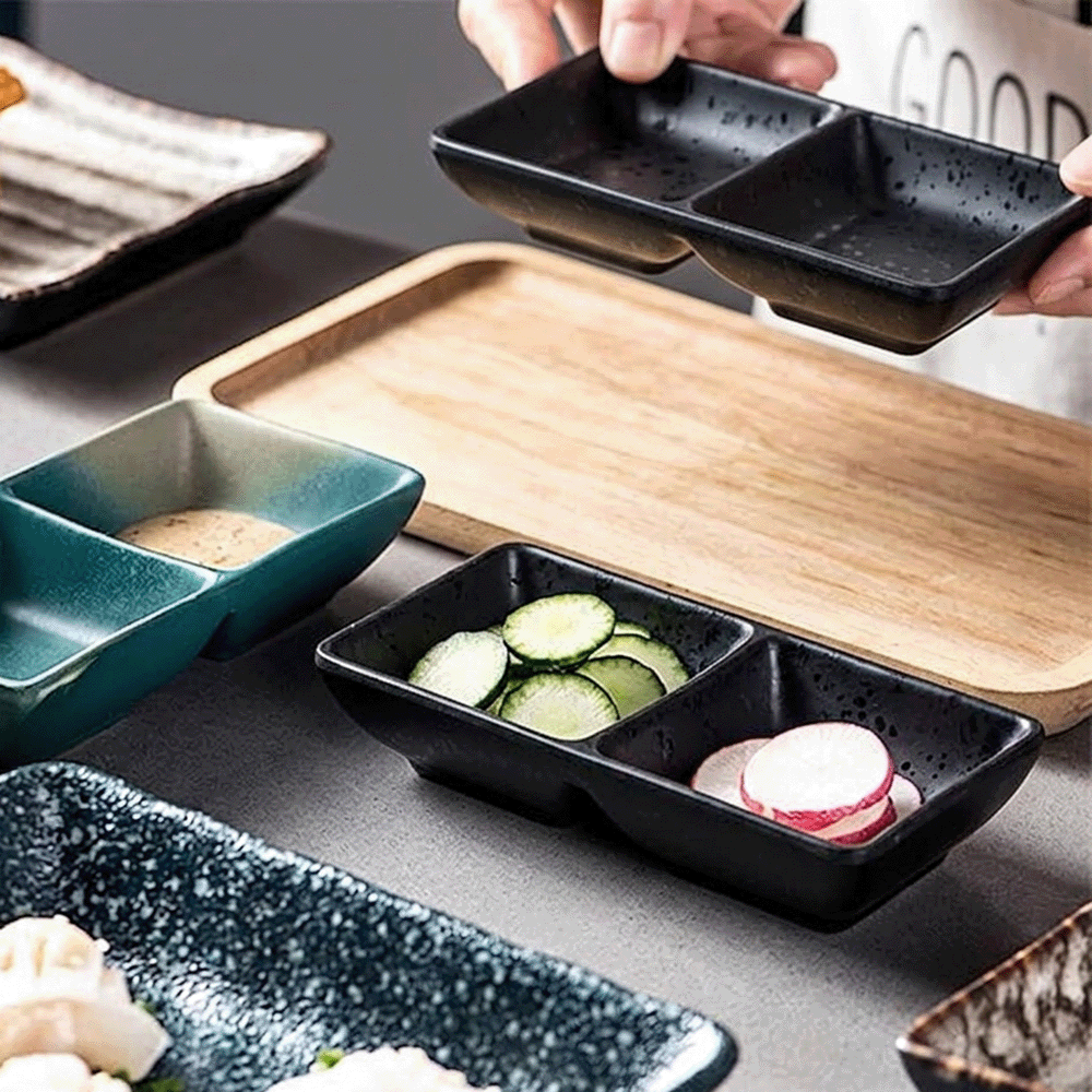 Chef preparing sushi with cucumber and radish slices in small black trays on a wooden board